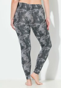 Leggings a fantasia animale nera e grigia con un design aderente, tessuto morbido e vita alta, che si estendono fino alla caviglia.