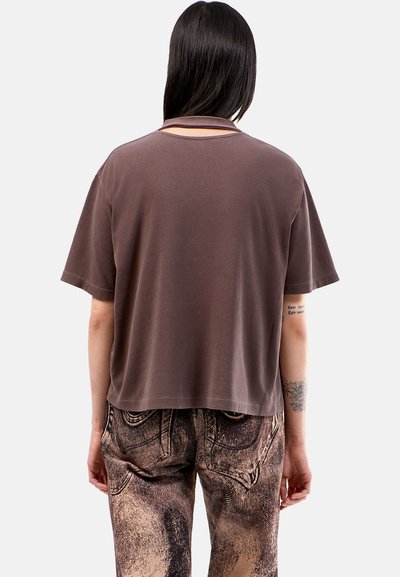Camiseta marrón de gran tamaño con mangas cortas, textura suave y corte holgado. Presenta un escote redondeado sutil y un diseño de espalda partida.