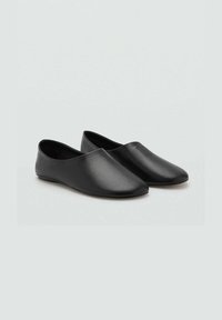 Scarpe nere slip-on con una finitura liscia e testurizzata, design a punta e suola a profilo basso. Senza hardware o decorazioni visibili.