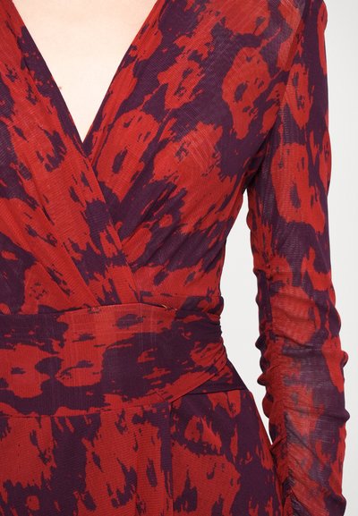 Punainen ja violetti kuviollinen mekko, jossa on syvä V-pääntie, pitkät hihat ja rypytystiedot ranteissa, valmistettu teksturoidusta kankaasta.