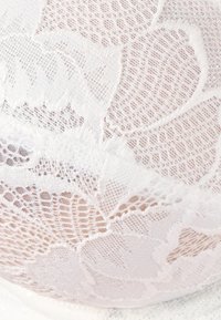 Witte kant stof met ingewikkelde bloempatronen en een zachte, delicate textuur, met een lichte glans en semi-doorzichtige uitstraling.