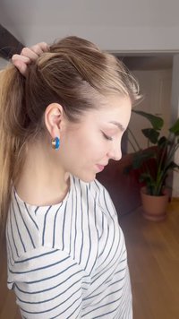 Blå og gull øreringer med sirkulært design. Stripete skjorte i hvitt og marineblått. Glatt tekstur, semi-casual stil. Naturlig hår trukket tilbake.