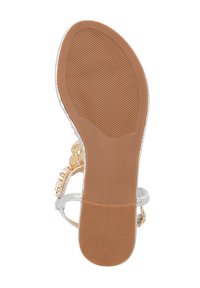 Flad sandal med en tekstureret brun gummisål, sølvremme med guld detaljer og en dekorativ arrangement af gennemsigtige sten.