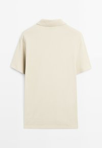 Béžové polo tričko s krátkými rukávy a klasickým límečkem, vyrobené z hladkého, texturovaného materiálu a s čistým, minimalistickým designem.