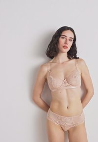 Podprsenka a nohavičky v nude farbe s čipkovým lemovaním, ozdobené kvetinovými vzormi a jemným povrchom. Navrhnuté pre pohodlie s nastaviteľnými ramienkami.