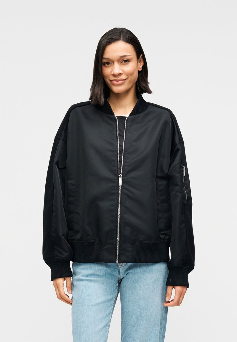 Μαύρο μπουφάν τύπου bomber με φερμουάρ μπροστά, ριμπ μανσέτες και τελείωμα, καθώς και πλαϊνές τσέπες. Διαθέτει λείο, γυαλιστερό ύφασμα και άνετη εφαρμογή.