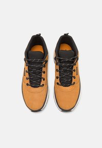 Brown suede sneakers with black textile accents, textured laces, and a white outsole, featuring a padded collar for comfort.