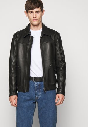 Schwarze Lederjacke mit einem Frontreißverschluss, großem Kragen und Seitentaschen. Verfügt über eine mit Reißverschluss versehene Armtasche und eine glatte Textur.