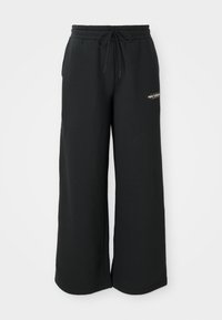 Pantalons de survêtement larges noirs en tissu doux, dotés d'une taille élastique avec cordon de serrage et d'un petit logo sur le côté gauche.