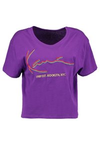 Lila bomullstopp med korta ärmar, prydd med färgglad broderad text "Kani" och "1989 EST. BROOKLYN, NYC" på framsidan.