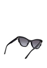 Gafas de sol de estilo cat-eye en color negro con lentes degradados en gris, montura de plástico brillante, bordes esculpidos y detalles en metal en las bisagras.