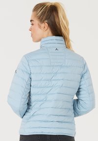 Lysblå polstret jakke med opretstående krave, vandret syninger og sort logo-detalje på skulderen. Struktureret stoffinish.