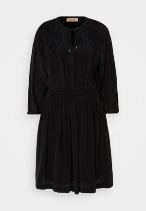 Crna haljina od mekanog materijala s okruglim izrezom, zatvaranjem na vezanje, dugim rukavima i nabranim suknjom. Ima elastičnu struk.