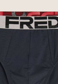 Slip in cotone blu navy con una larga fascia elastica in vita con la scritta "FRED" in grassetto nero su sfondo grigio chiaro.