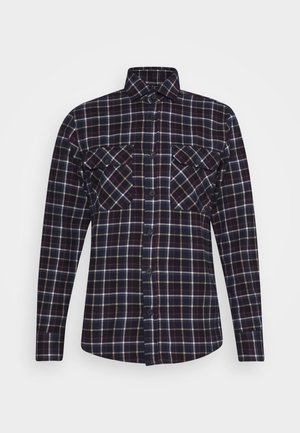 Camicia a maniche lunghe con bottoni, motivo a quadri nero, bianco e marrone, due tasche frontali sul petto con bottone e colletto classico.