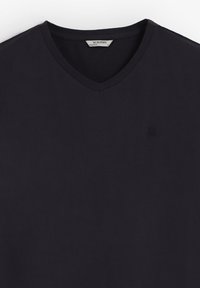 Camiseta de color azul marino oscuro con cuello en V, hecha de algodón suave, con un logo bordado en el lado izquierdo del pecho y mangas cortas.