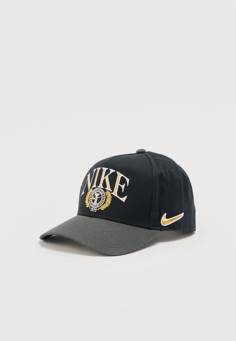 Black and gray Nike cap with embroidered yellow logo, "NIKE" text, laurel wreath, and "1972" on front and yellow swoosh on the side.