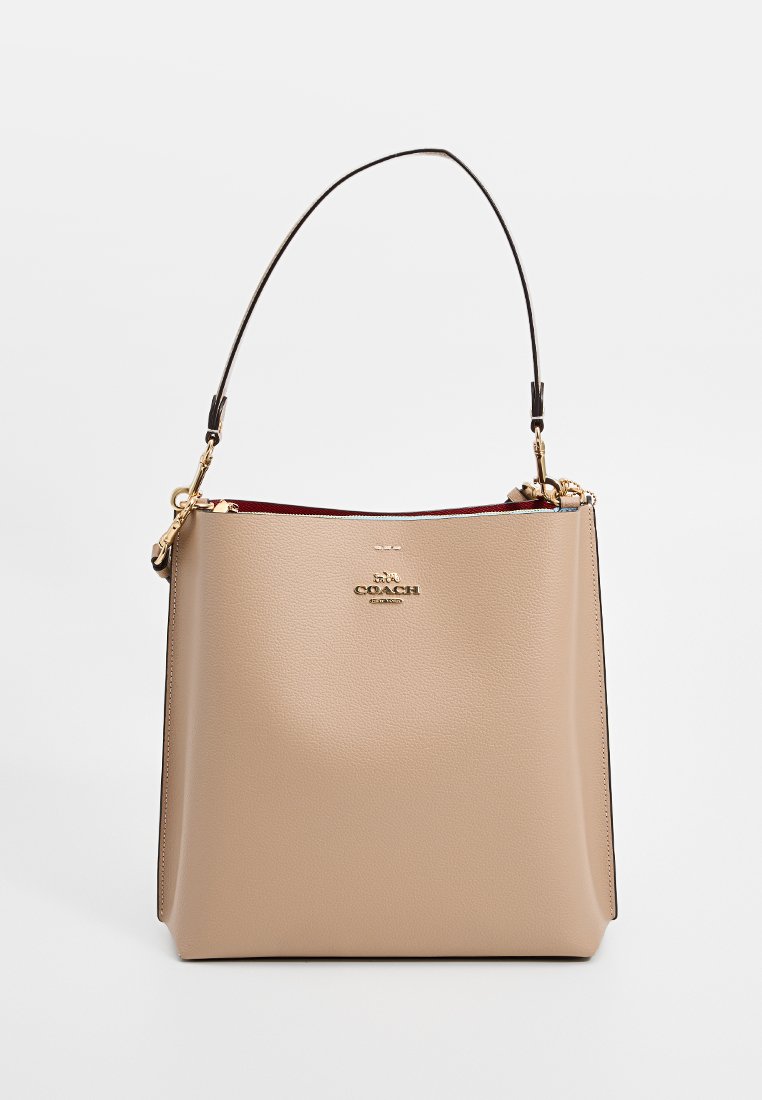 Sac seau en cuir beige au design structuré, avec une poignée supérieure unique et une plaque de logo. Présente un intérieur rouge contrasté et des finitions en tone doré.