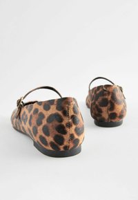Des chaussures plates à imprimé leopard en tissu doux, avec un petit talon, ornées d'une sangle et d'une boucle, dans des tons de brun et de noir.