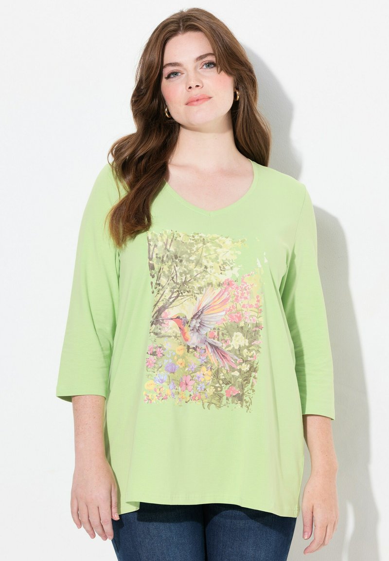 Lichtgroene, lange mouwen t-shirt met een levendige bloemen- en kolibriprint aan de voorkant. V-hals ontwerp. Zacht, rekbaar materiaal.