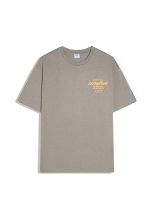 T-shirt taupe à manches courtes avec texte jaune sur la poitrine gauche indiquant « Trop occupé à être insouciant pour répondre à vos appels. »