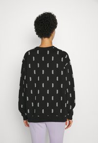 Felpa nera in cotone, con un motivo a logo bianco ripetuto. Ha un collo rotondo, maniche lunghe e polsini a coste.
