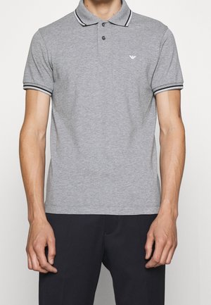 Grau meliertes Poloshirt mit schwarz-weiß gestreiftem Kragen und Bündchen. Auf der linken Brust befindet sich ein kleines Logo. Das Material wirkt glatt und leicht.