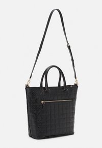 Černá kožená tote taška s texturovaným, embosovaným vzorem. Má dvojité uchycení, odnímatelný ramenní popruh a přední kapsu na zip.