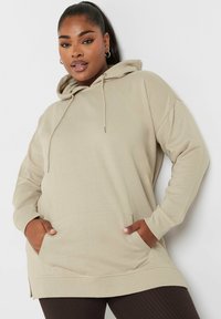 Felpa beige realizzata in tessuto morbido, con tasca frontale, cappuccio con cordino e polsini a costine, progettata con un design oversize.