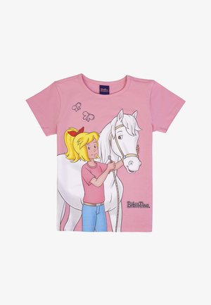 Ragazza con coda di cavallo bionda, maglietta rosa e pantaloni blu che tiene le redini di un cavallo bianco, con due farfalle sopra e il testo "Bibi & Tina".