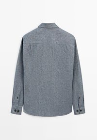 Grijze lange mouw shirt met subtiele textuur, kraag, knoopsluiting met twee knopen, rugnaad en een rechte zoom.