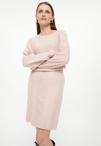 Rosa Strickkleid im Kabelstrickdesign, mit Rundhalsausschnitt und gerippten Bündchen. Figurbetonter, knielanger Schnitt.