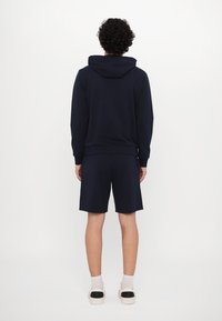 Navy blue hoodie and matching shorts in cotton blend. Hoodie has a drawstring and ribbed cuffs; shorts feature an elastic waistband.