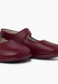 Scarpe in pelle bordeaux con punta rotonda, bordi scallop e una singola fascia sopra il piede. Texture liscia con suola flessibile.