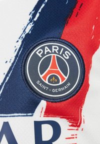Tissu blanc avec des motifs de coups de pinceau rouges et bleus. Présente un écusson brodé circulaire avec "PARIS SAINT-GERMAIN" et le logo de la Tour Eiffel.