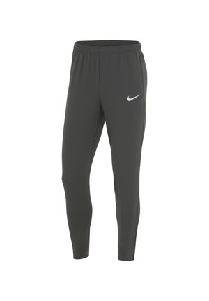 Grijze sportbroek met een tapered ontwerp, elastische tailleband en subtiele rode accenten aan de zijkanten. Voorzien van een wit Nike-logo op de voorkant.