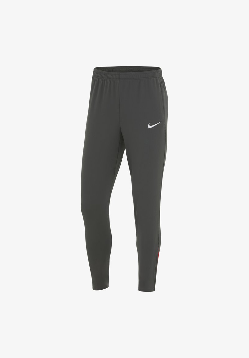 Pantaloni sportivi grigi con design affusolato, vita elastica e sottili accenti rossi sui lati. Presentano un logo Nike bianco sul davanti.