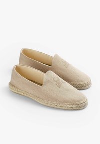 Beige espadriller lavet af herringbone-stof med en vævet jute-sål. Har et broderet kranie-design på fronten. Slip-on stil.