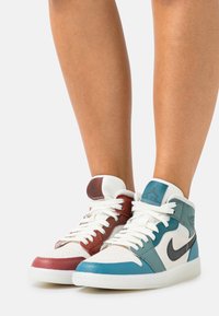 Hoge sneakers met een ontwerp van wit, rood en teal leer, met een getextureerd oppervlak en kenmerkende branding op de tong.