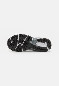Black and gray running shoe outsole featuring a textured rubber surface with geometric tread patterns and white accents.