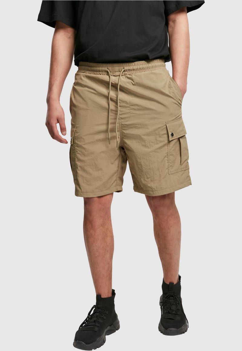 Beige cargo shorts yang terbuat dari kain ringan, dilengkapi dengan pinggang tali serut, saku samping, dan saku tambalan dengan Penutup snap.