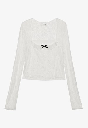 Fehér, hosszú ujjú, csipkés blúz négyzetes nyakkivágással, fodros szegéllyel és kis fekete masnival az elülső középen.