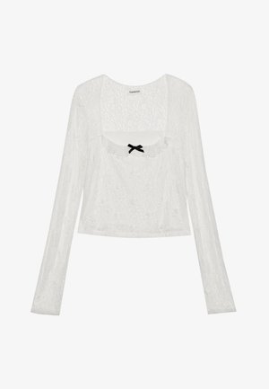 Blusa de renda branca de manga longa com decote quadrado, detalhes em babados e um pequeno laço preto ao centro da frente.