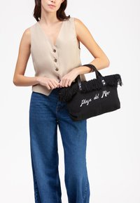 Borsa a spalla nera intrecciata con dettagli frangiati, caratterizzata da ricamo "Playa del Mar" in bianco e manici in pelle nera a contrasto.