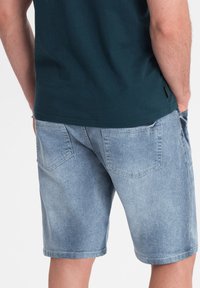 Shorts de mezclilla en azul claro, con un ajuste relajado, dos bolsillos traseros con una textura ligeramente desgastada y un dobladillo recto.