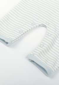 Pantalons pour bébé rayés bleu clair et blanc avec des boutons-pression le long de la couture intérieure sur un fond blanc.