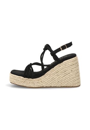 Sandalia cuña negra con tiras, hebilla en el tobillo y suela plataforma de yute natural trenzado, vista lateral sobre fondo blanco.