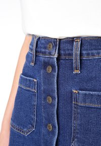 High-waisted denim skirt in medium blue, featuring a five-button closure, two front pockets, and visible stitching accents.