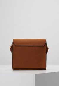 Brązowa torebka na ramię z ekoskóry o usztywnionym kształcie, z klapką zamykającą i złotymi ozdobami. Gładka faktura i minimalistyczny design.