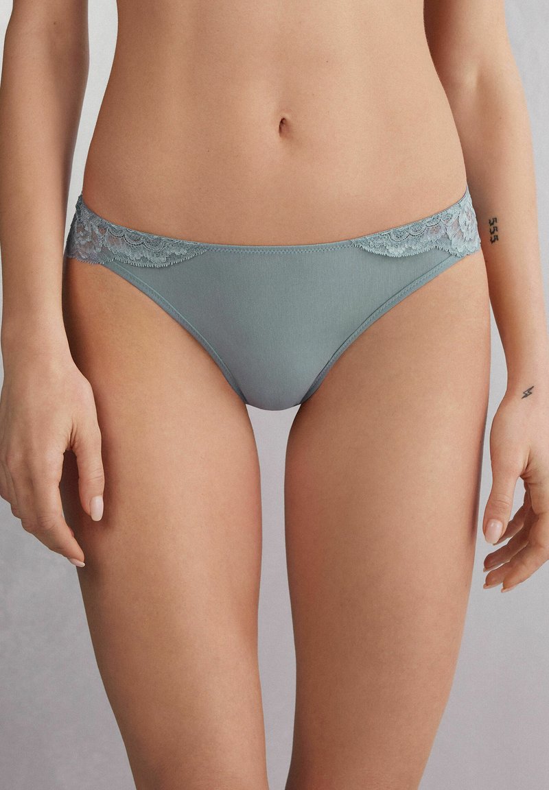 Lichtblauwe onderbroek met een kanten rand aan de taille, met een zachte textuur en een low-rise ontwerp. Kanten details voegen een decoratief element toe.